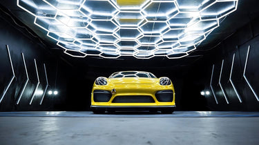 Yellow car parked under hexagon LED grid lights, with shadows cast on the car creating a dramatic effect