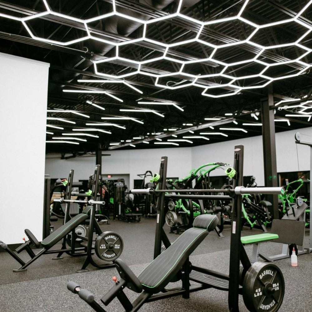 Gym-goers working out under a ceiling of hexagon LED grid lights, enhancing the fitness environment with dynamic and effective lighting