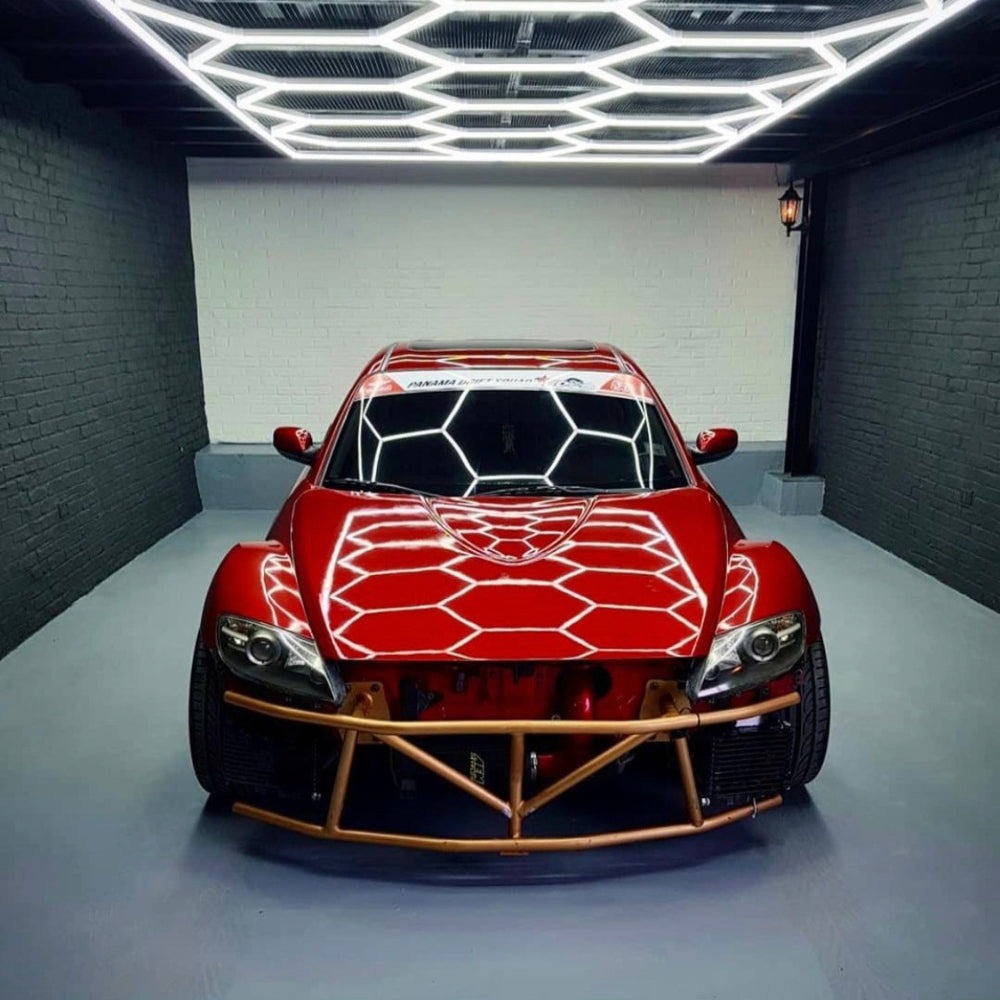 Red car below hexagon LED grid lights on the roof, creating dramatic shadows on the vehicle