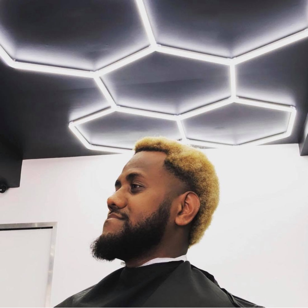 Cutting hair in a salon with hexagon LED grid lights above, providing bright and focused illumination