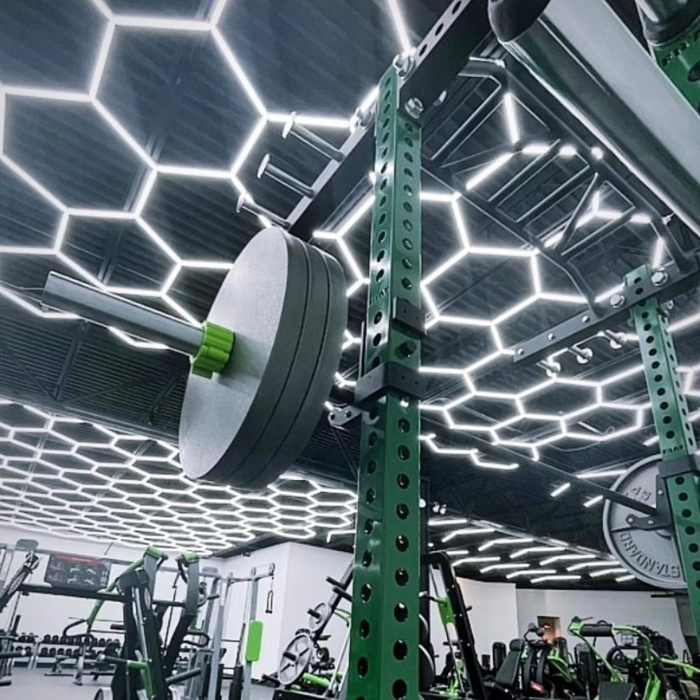 Fitness gym with hexagon LED grid lights covering all the roofs, creating a stunning and cohesive lighting design throughout the space